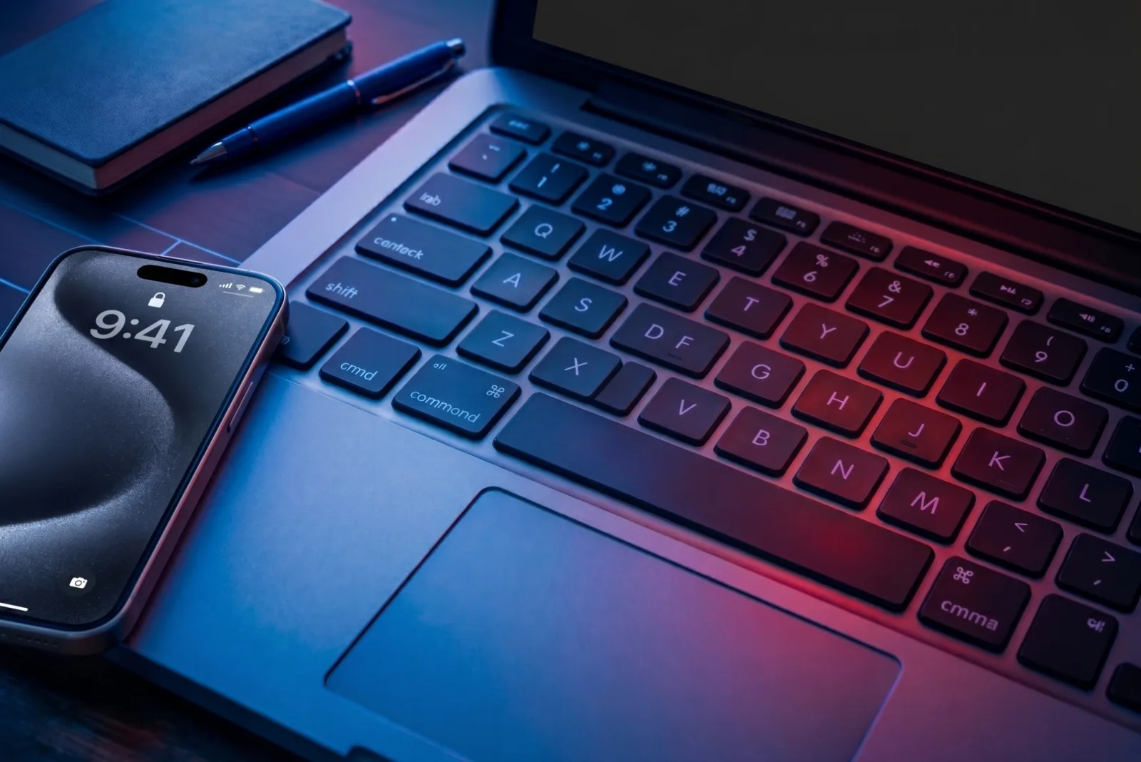 A locked smartphone resting on a laptop keyboard under blue and red lighting